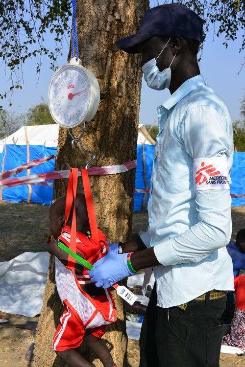 An MSF nurse aid weighs a baby before a medical consultation in the MSF mobile clinic set-up in Riang, Jonglei State.  Copyright: Damaris Giuliana/MSF