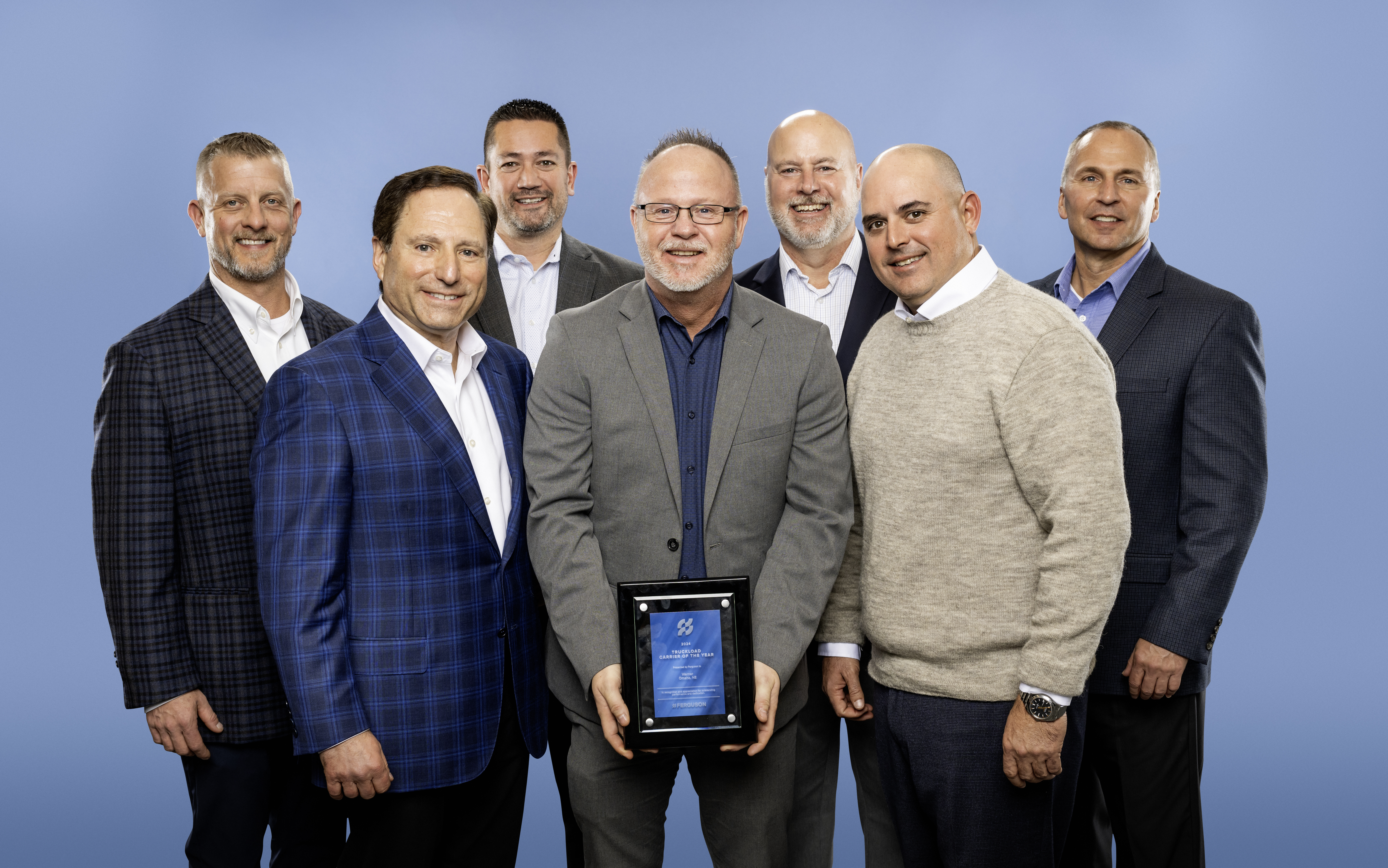 Photo courtesy of Ferguson : Werner – (from left to right) –  Front Row : Michael Jacobs, SVP of Supply Chain Ferguson; Pat Kortus (holding the award), Operations Supervisor; David Simons, VP of Global Logistics Ferguson.  Back Row : Jim Waszak, Senior Vice President – Dedicated; Eric Downing, Executive Vice President and Chief Operations Officer; Pete Mullenburg, Director – Dedicated; Kevin Schwarting, Vice President – Dedicated. 