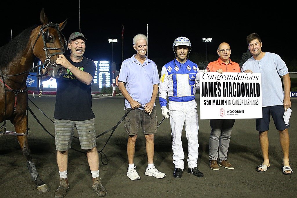 James MacDonald is congratulated by Bill McLinchey, Director of Standardbred Racing, and is joined by Dewitt This Moment's connections of Paul Ritchie, Jim Ritchie and Nick Ritchie. (New Image Media)