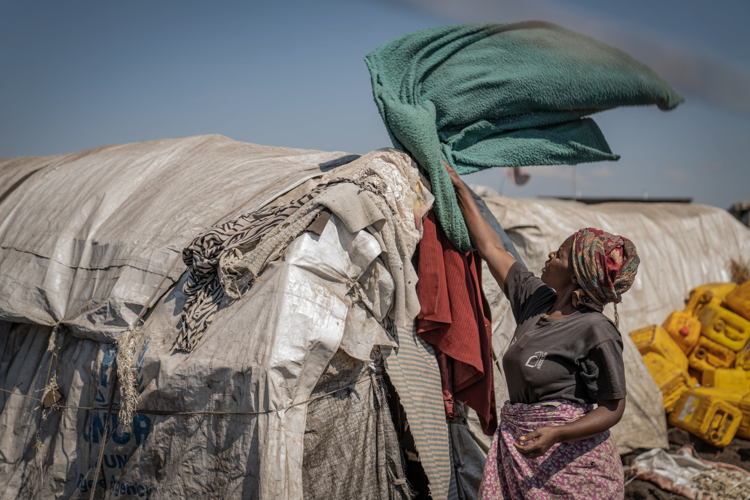 Esther spreads blankets over her shelter in the Elohim camp. Displaced families live in difficult and precarious conditions. Copyright: Moses Sawasawa