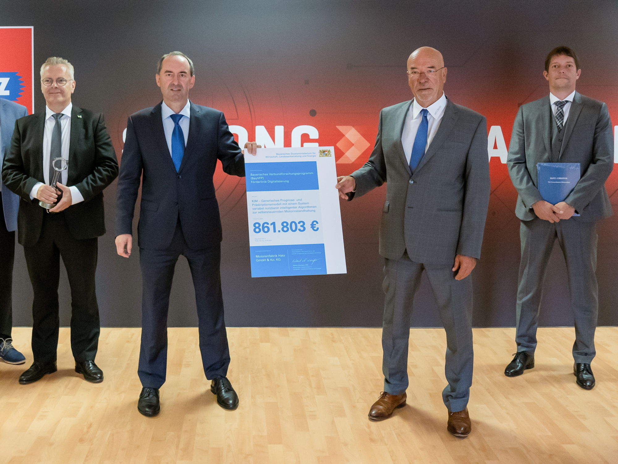 As part of a company visit, the Bavarian Minister for Economic Affairs Hubert Aiwanger (second from left) presents the funding certificate for the joint KIM project to the main shareholder Wolfram Hatz (second from right) as well as CEO Bernd Krüper (left) and CTO Dr.-Ing. Simon Thierfelder.