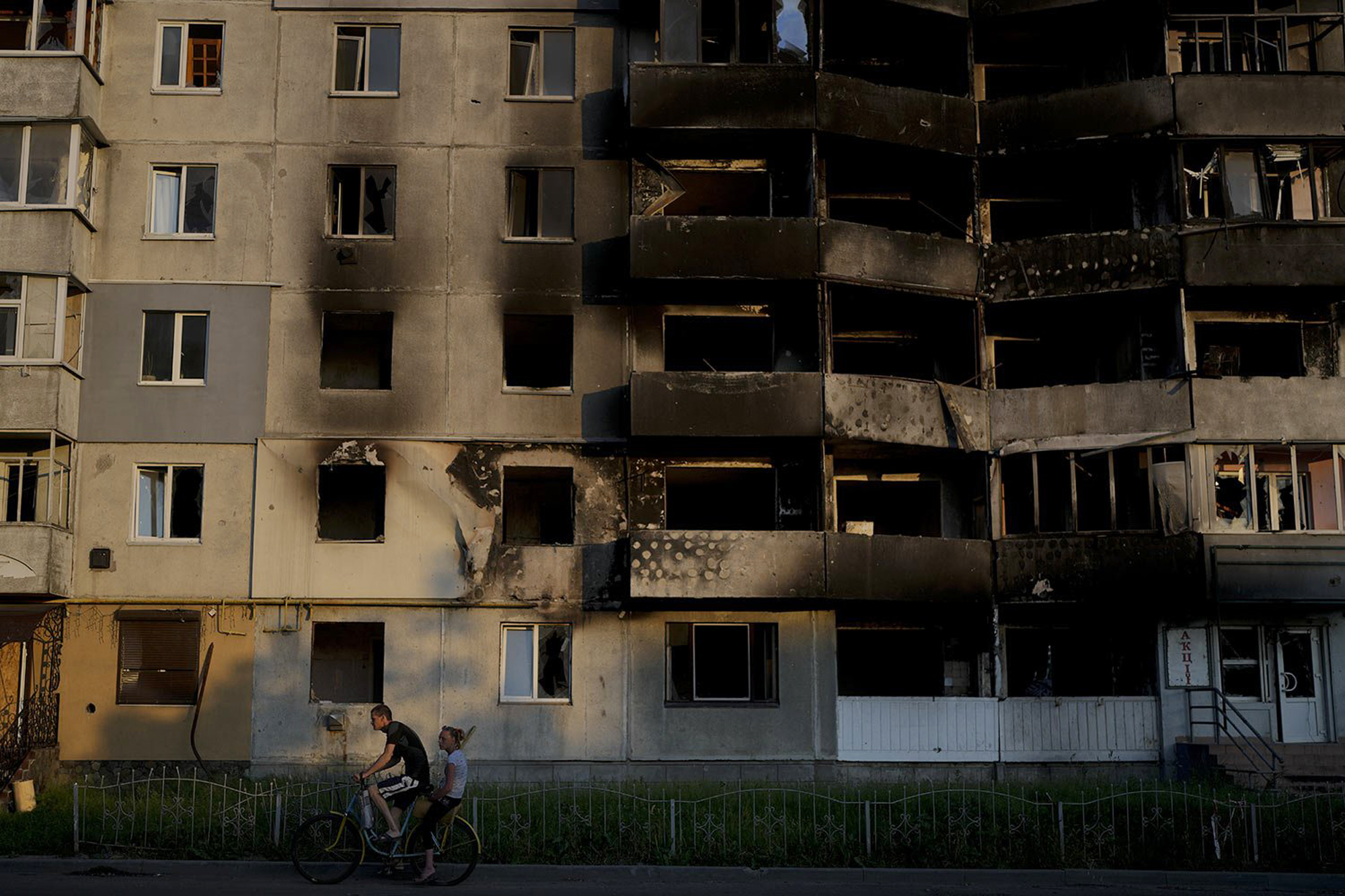 A man rides a bicycle past a building destroyed in Russian attacks in Borodyanka, on the outskirts of Kyiv, Ukraine. AP Photo/Natacha Pisarenko