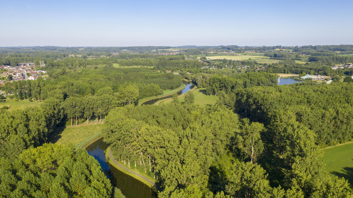 Luchtfoto boven de Dender, links bos Idegem, rechts vijver en zwembad domein De Gavers - copyright: Travel for Motion