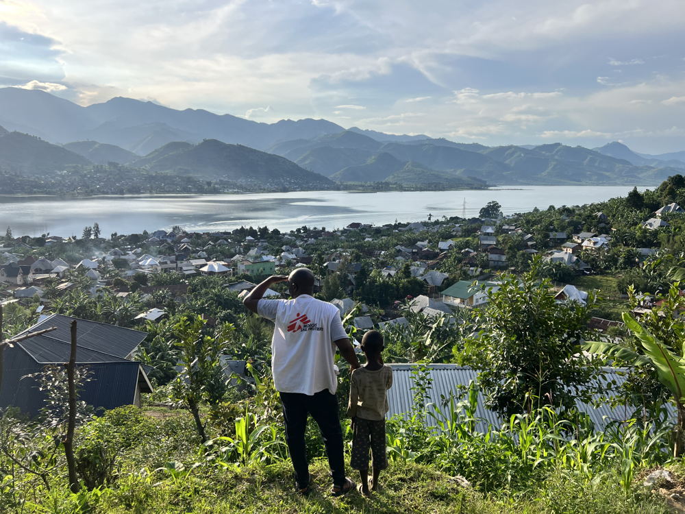 An MSF staff member and a child look at the town of Minova and Lake Kivu from the top of a hill. South Kivu province, eastern DRC. Copyright: Igor Barbero/MSF 