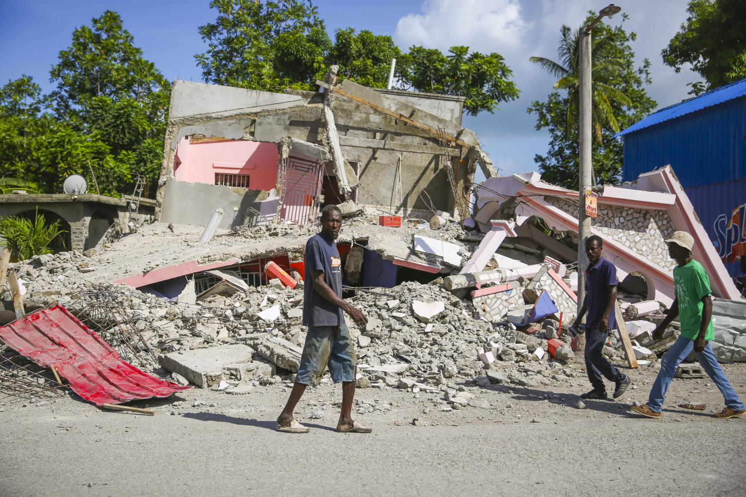 People walking in front of a destroyed building in a street of Les Cayes. Copyright: Steven Aristil / MSF
