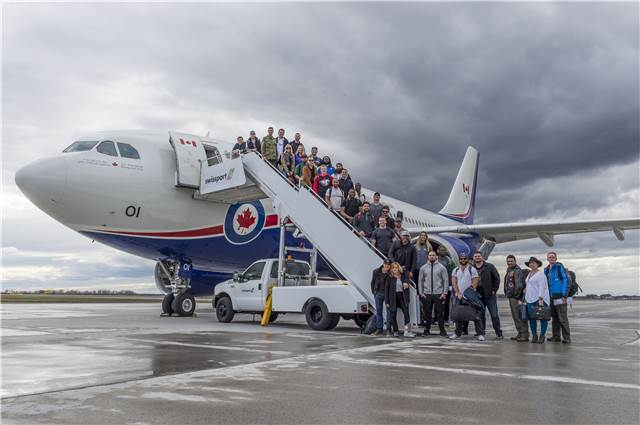 Le brigadier-général Paul Rutherford, des joueurs de la Ligue canadienne de football, le groupe The Dallas Smith Band et l’humoriste John Sheehan sont prêts à monter dans l’avion à Ottawa, en Ontario, pour visiter l’opération UNIFIER et l’opération Reassurance. Photo : CplC Mathieu Gaudreault, Caméra de combat des Forces canadiennes