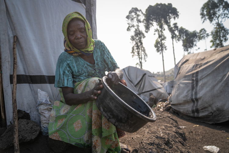 Daphrose, Esther's mother-in-law and grandmother to Tuliya and Rebecca, cleans a kitchen utensil in front of her tent in Elohim. Copyright: Moses Sawasawa