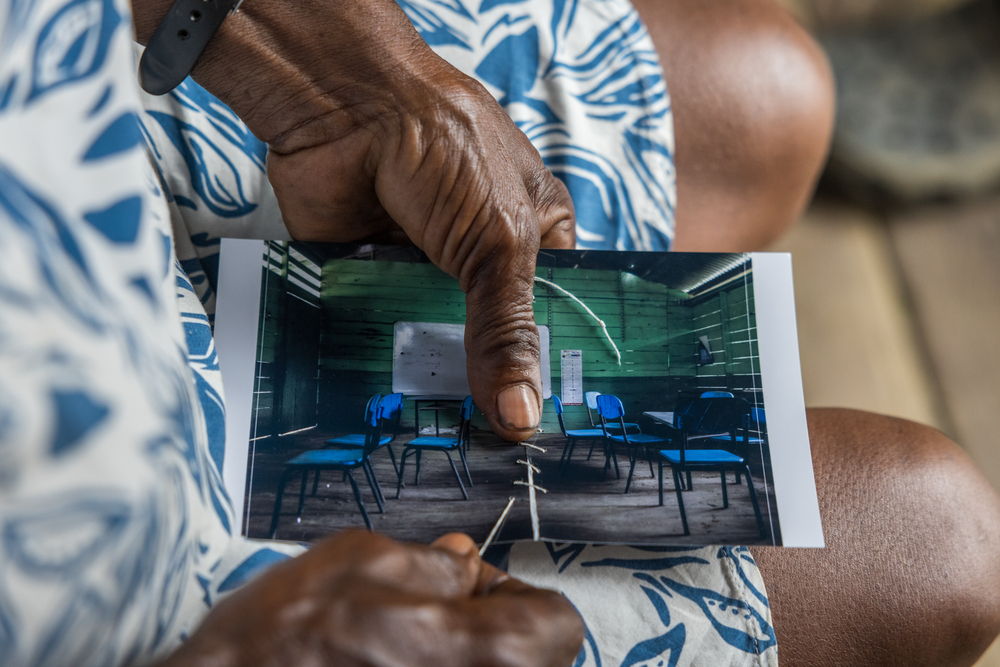 Margarita Rojas Mena, in Mojaudó, stitched up the photograph of the community school, wounded by bullets from an armed confrontation. Mojaudó, Alto Baudó, Chocó.