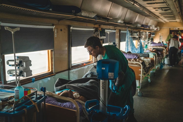 Unique Identifier Code / URN: MSB127252 Title: Doctors on Rails - MSF Medicalised train in Ukraine Copyright: Andrii Ovod Countries: Ukraine Date taken / Date Recorded: 20 May, 2022 Caption / Description: MSF nurse aid, Dmytro Mohylnytskyi, monitors a war-wounded patient inside the intensive care unit (ICU) of the MSF medical team during a journey from Pokvrosk in eastern Ukraine, to Lviv in western Ukraine. The journey takes approximately 20 hours. Since 31 March, we have transported more than 600 patients. Unique Identifier Code / URN: MSB127252 Title: Doctors on Rails - MSF Medicalised train in Ukraine Copyright: Andrii Ovod Countries: Ukraine Date taken / Date Recorded: 20 May, 2022 Caption / Description: MSF nurse aid, Dmytro Mohylnytskyi, monitors a war-wounded patient inside the intensive care unit (ICU) of the MSF medical team during a journey from Pokvrosk in eastern Ukraine, to Lviv in western Ukraine. The journey takes approximately 20 hours. Since 31 March, we have transported more than 600 patients.