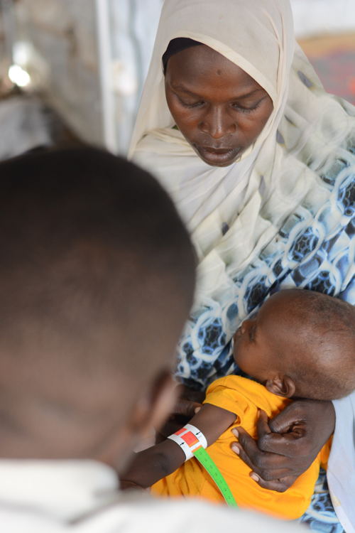 Saadiah, with her daughter at the MSF clinic in Zamzam Camp, North Darfur, observes as a nurse performs a MUAC screening in the triage room to assess the child’s health. Zamzam camp near El-Fasher | 30/08/2024 | Photographer: Mohammed Jamal.