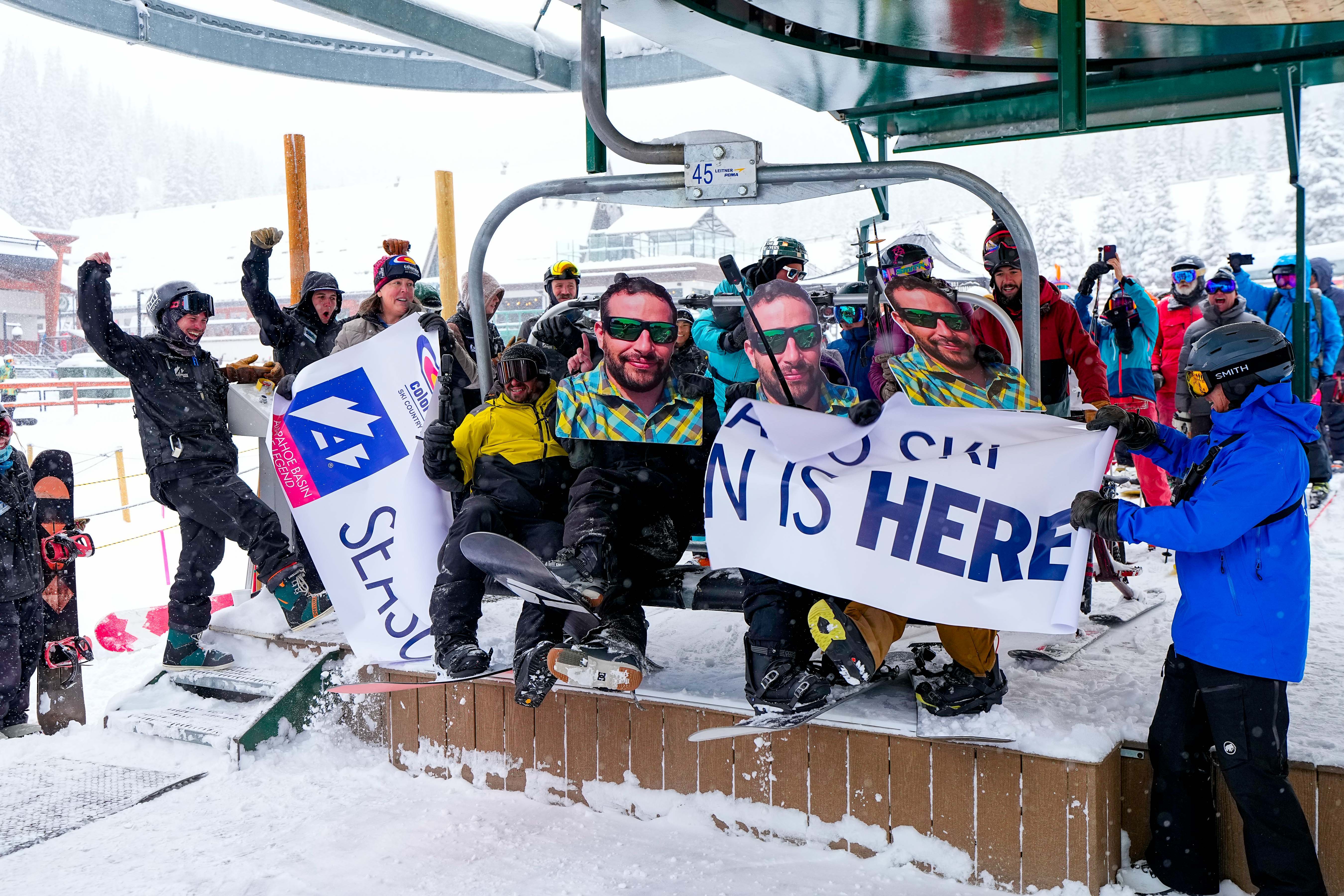 Happy skiers and snowboarders break through the banner on the first chair of the 2023-24 Colorado ski season at Arapahoe Basin