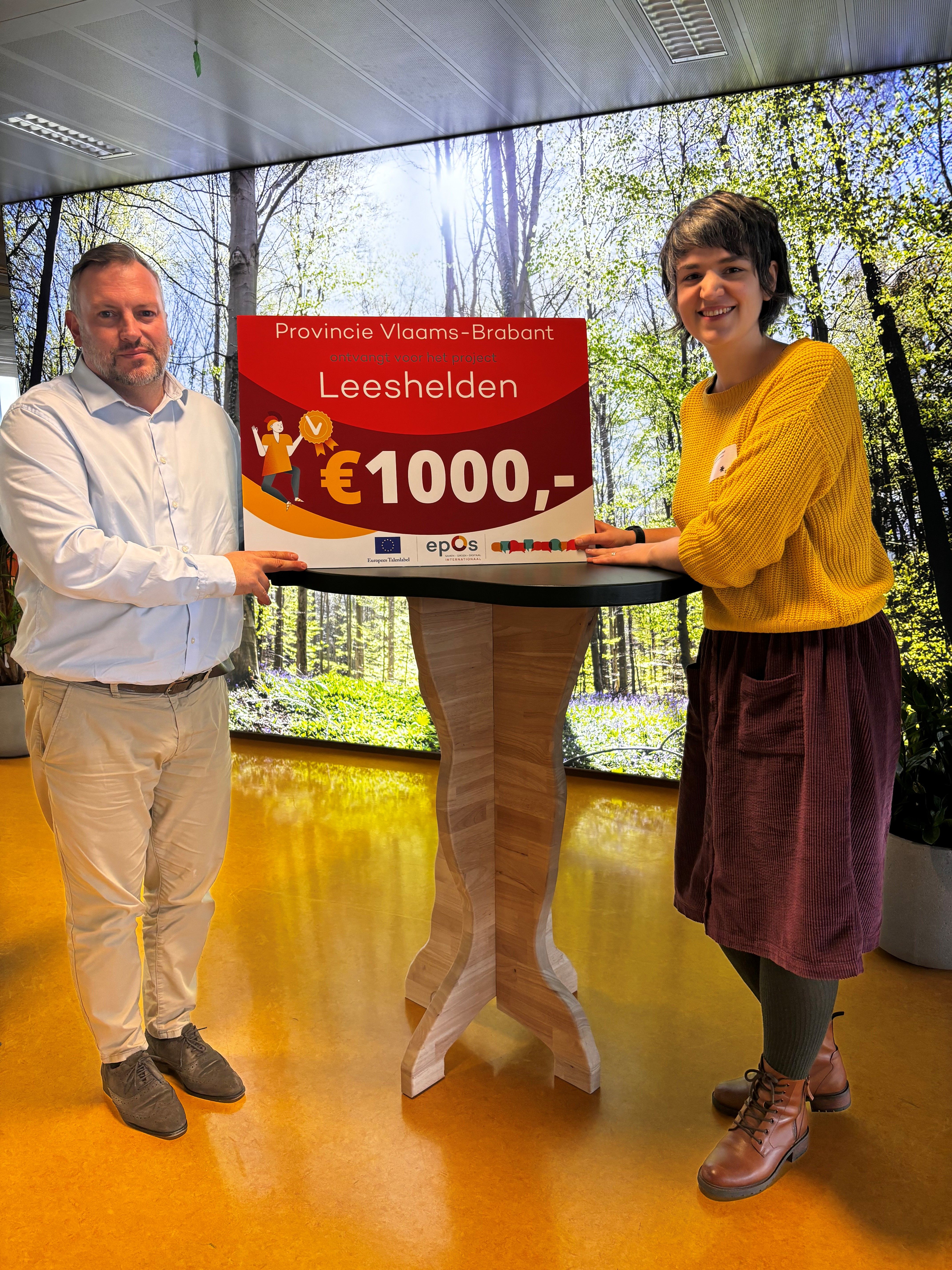 Gedeputeerde Coppens neemt de winnende 'Leeshelden'-cheque in ontvangst.