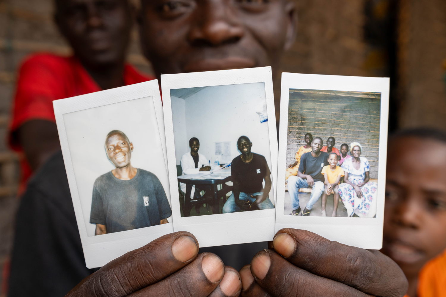 Living with HIV/Aids through Conflict and Displacement - Macomia Constâncio Paulo Felix, a 43 years-old Mozambican carpenter, holds three photos – one of himself, one of him during a medical appointment with MSF’s Clinical Officer who is accompanying his HIV treatment (Mussa), and the last with his family (Photos taken/offered by MSF FCM Martim Gray Pereira following an interview).  Constâncio and his family were forced to flee their homes in Nkóe after non-state armed groups attacked their village in 2022. While displaced, they are living in Macomia Village, in Cabo Delgado, as they cannot return home due to insecurity.  In June 2022, Constâncio’s wife passed away due to HIV. Later that year, Constâncio also tested positive for HIV at MSF’s Clinic in Nanga, and has been receiving anti-retroviral treatment and support since then. Photographer: Martim Gray Pereira 