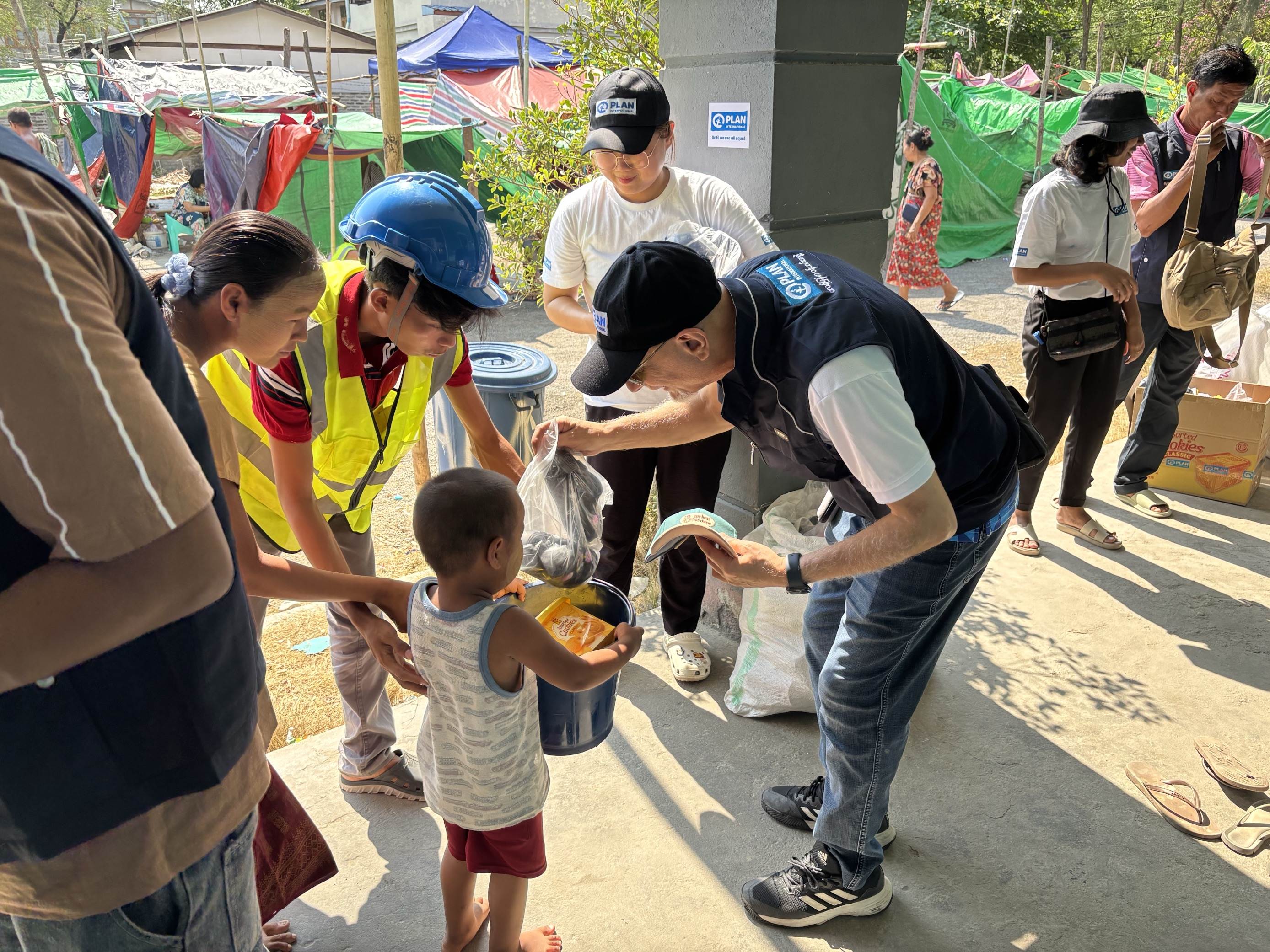 Un jeune garçon et sa mère au Myanmar reçoivent des articles essentiels de la part d'un collaborateur de Plan International. Un jeune garçon et sa mère au Myanmar reçoivent des articles essentiels de la part d'un collaborateur de Plan International.
