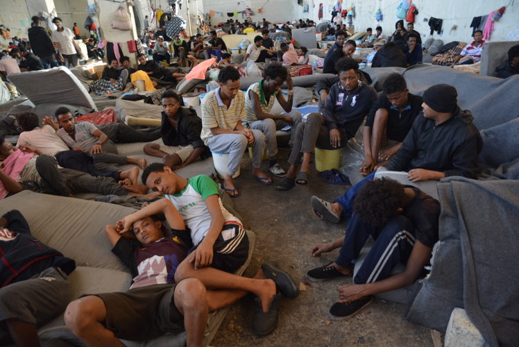 2) South of Tripoli, in the Nafusa Mountains, people in need of international protection and registered with the UNHCR as asylum seekers or refugees have been left stranded in detention for months – and in some cases years – with virtually no assistance. 

Between September 2018 and May 2019, at least 22 people died in detention, mostly from tuberculosis, in Zintan and Gharyan detention centres. Among the dead were young men, women and an eight-year-old child. 

In Zintan detention centre, some 700 people were locked up in an overcrowded agricultural warehouse, while 200 others were confined in a series of smaller buildings. © Jérôme Tubiana/MSF