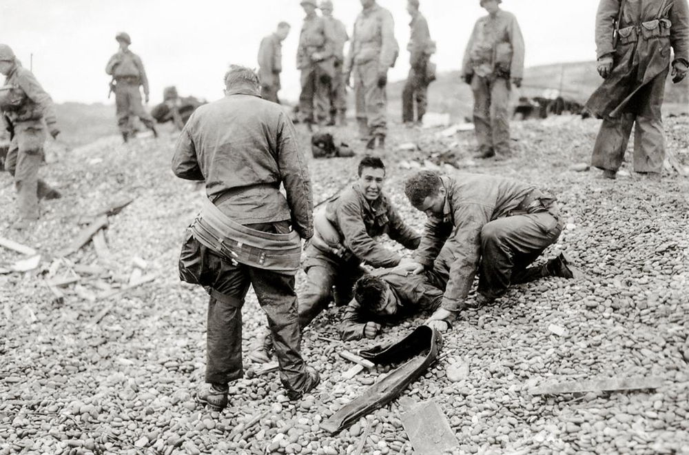 AKG2492477 In the Easy Red sector, Colleville-sur-Mer (Normandy, France): American soldiers from the 5th or 6th Engineer Special Brigade (ESB) try to help a comrade lying on his stomach. ©akg-images