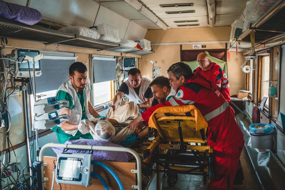 A severely war-wounded patient is moved from an ambulance stretcher to a bed inside the intensive care unit (ICU) of the MSF medical train, which transports war wounded and seriously ill people from eastern Ukraine to Lviv, in western Ukraine, where they can receive the specialsed care that they need. Photographer: Andrii Ovod 