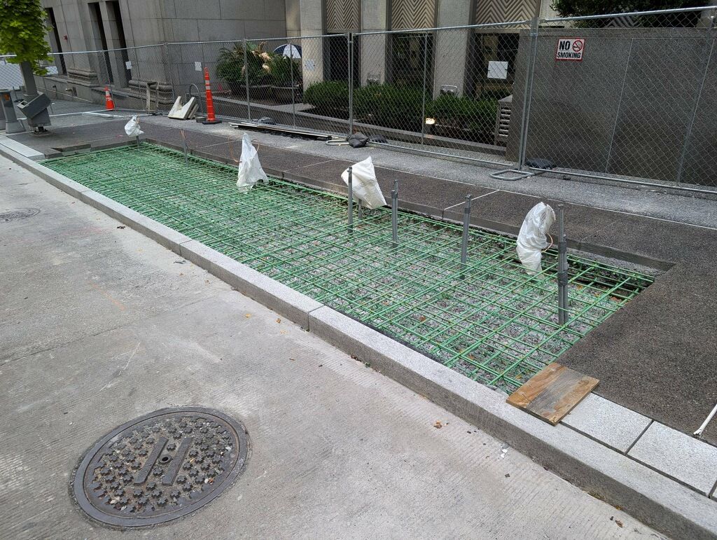 New exposed aggregate concrete sidewalk recently placed at Fifth Avenue and William Penn Place. The green steel rebar will support the concrete slab where ​ the new bus shelter will be placed. ​