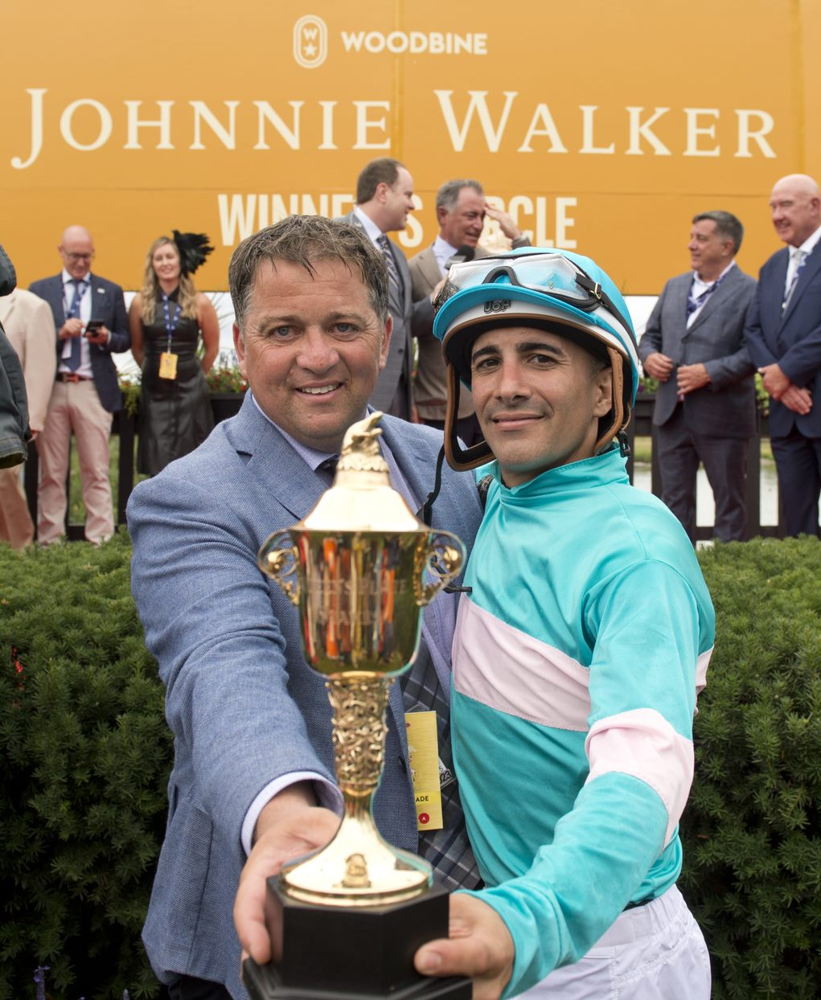 Moira's trainer Kevin Attard and jockey Rafael Hernandez holding the Queen's Plate trophy after their 2022 win at Woodbine (Michael Burns Photo)  