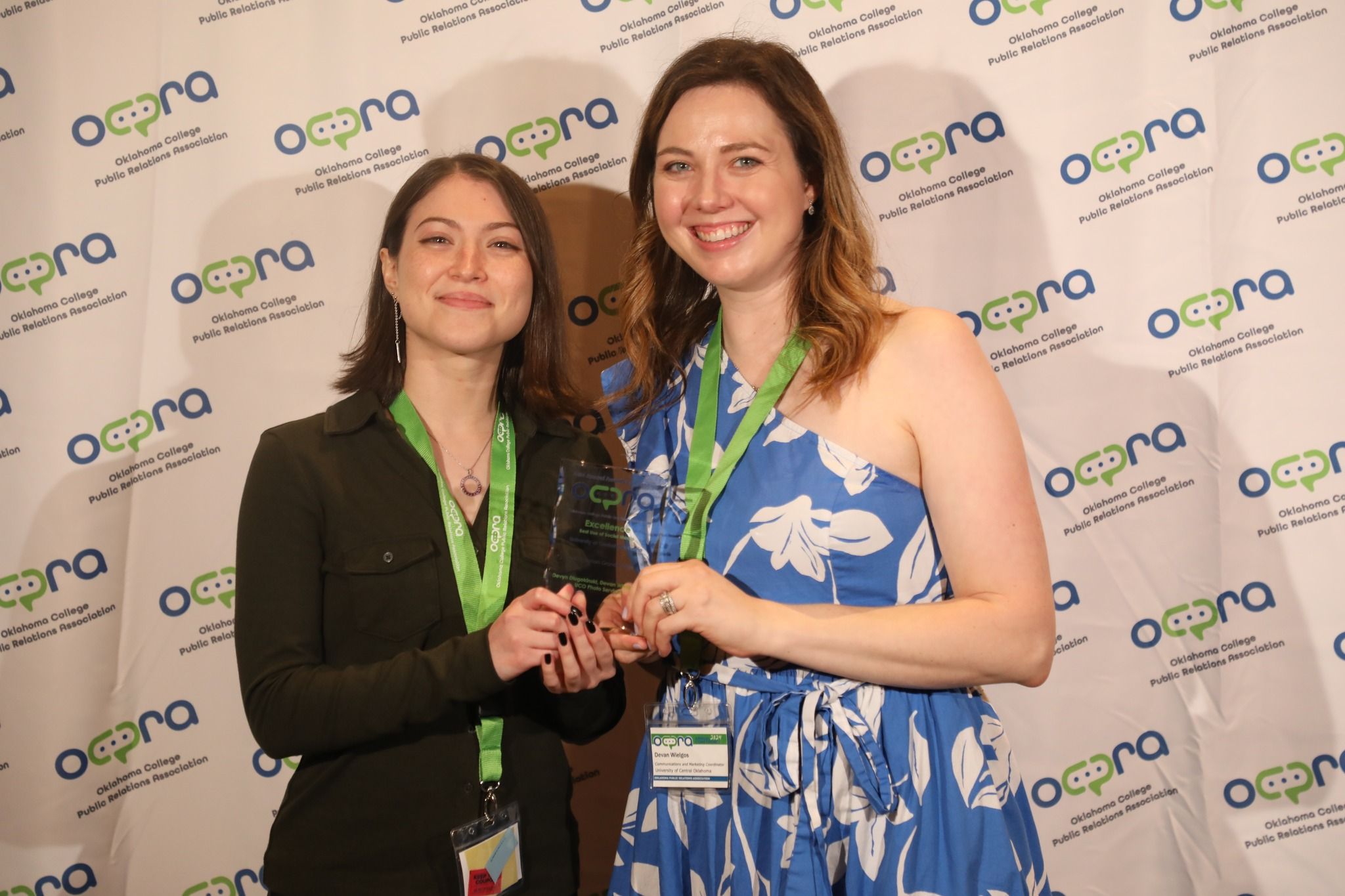 Two individuals pose for a photo with an award.