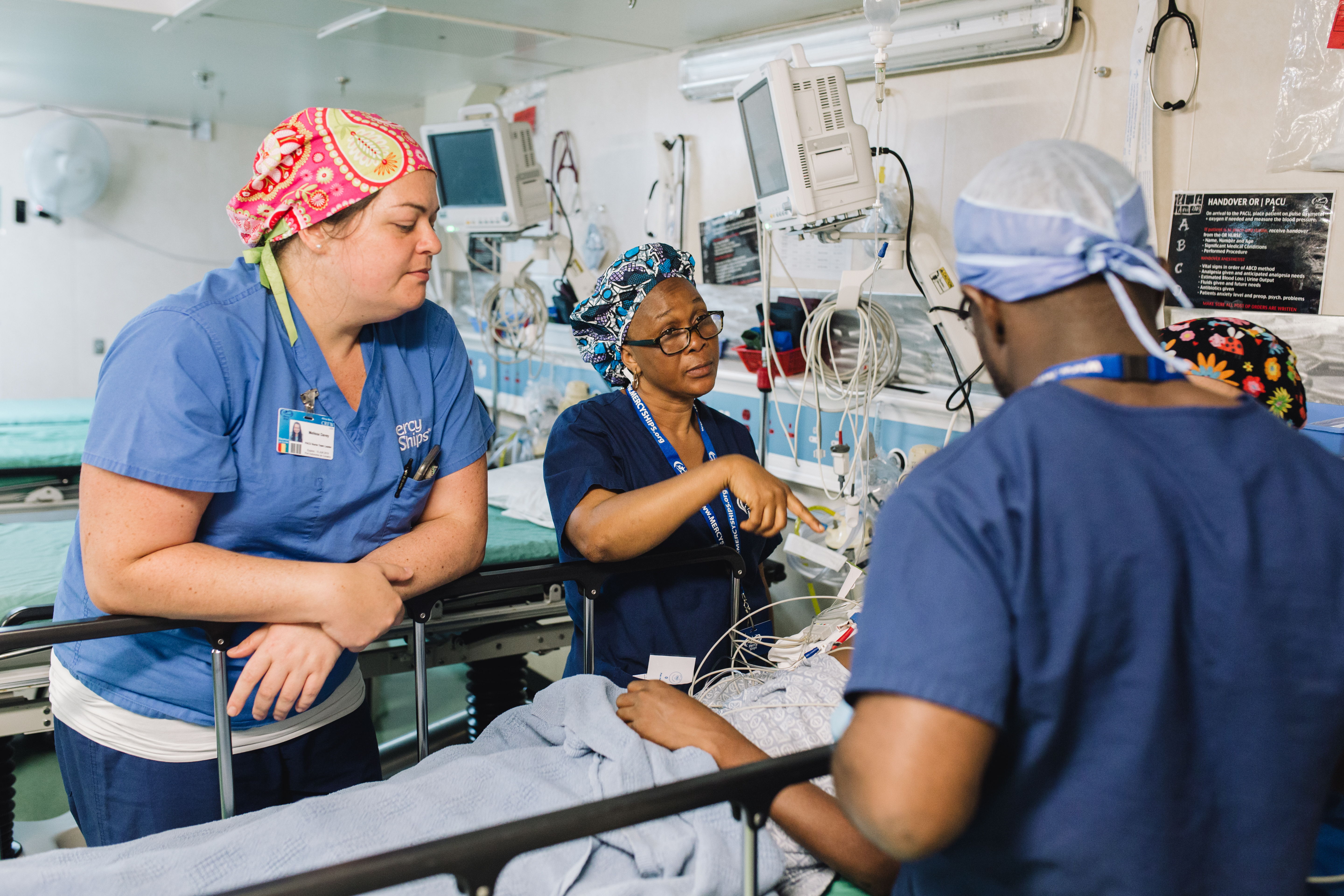 Volunteers check in on a patient in the Africa Mercy hospital ward. Volunteers check in on a patient in the Africa Mercy hospital ward.