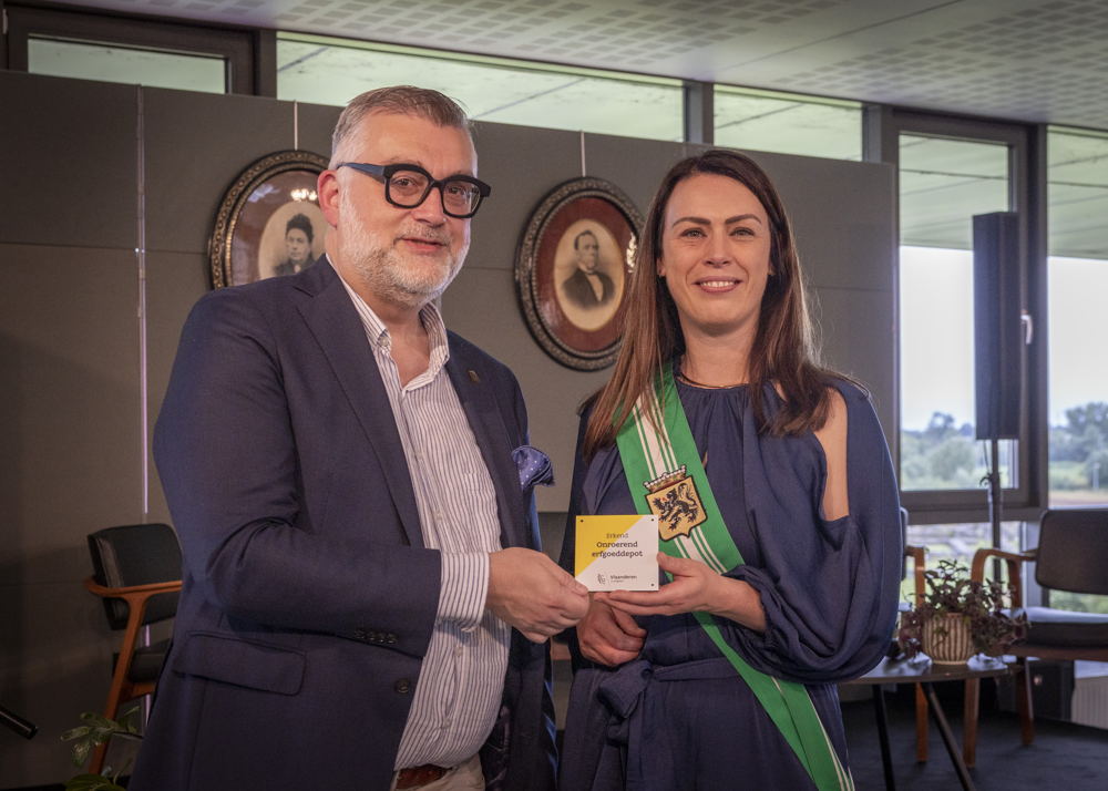 Peter De Wilde overhandigt het herkenningsteken voor erkend onroerenderfgoeddepot aan gedeputeerde An Vervliet