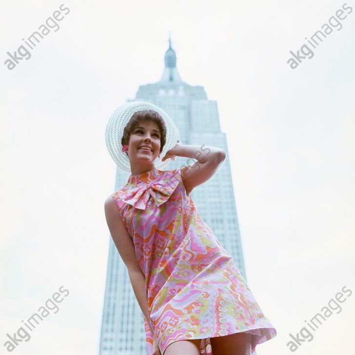 Young woman in a miniskirt in front of Empire State Building, 1960s. AKG2154653