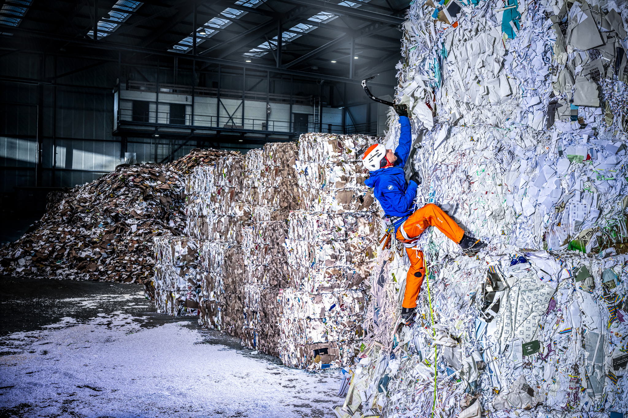 Jonas Schild klettert an Bergen aus Papiermüll in voller Eiskletterausrütung. (Foto: Rainer Eder/Mammut) Jonas Schild klettert an Bergen aus Papiermüll in voller Eiskletterausrütung. (Foto: Rainer Eder/Mammut)