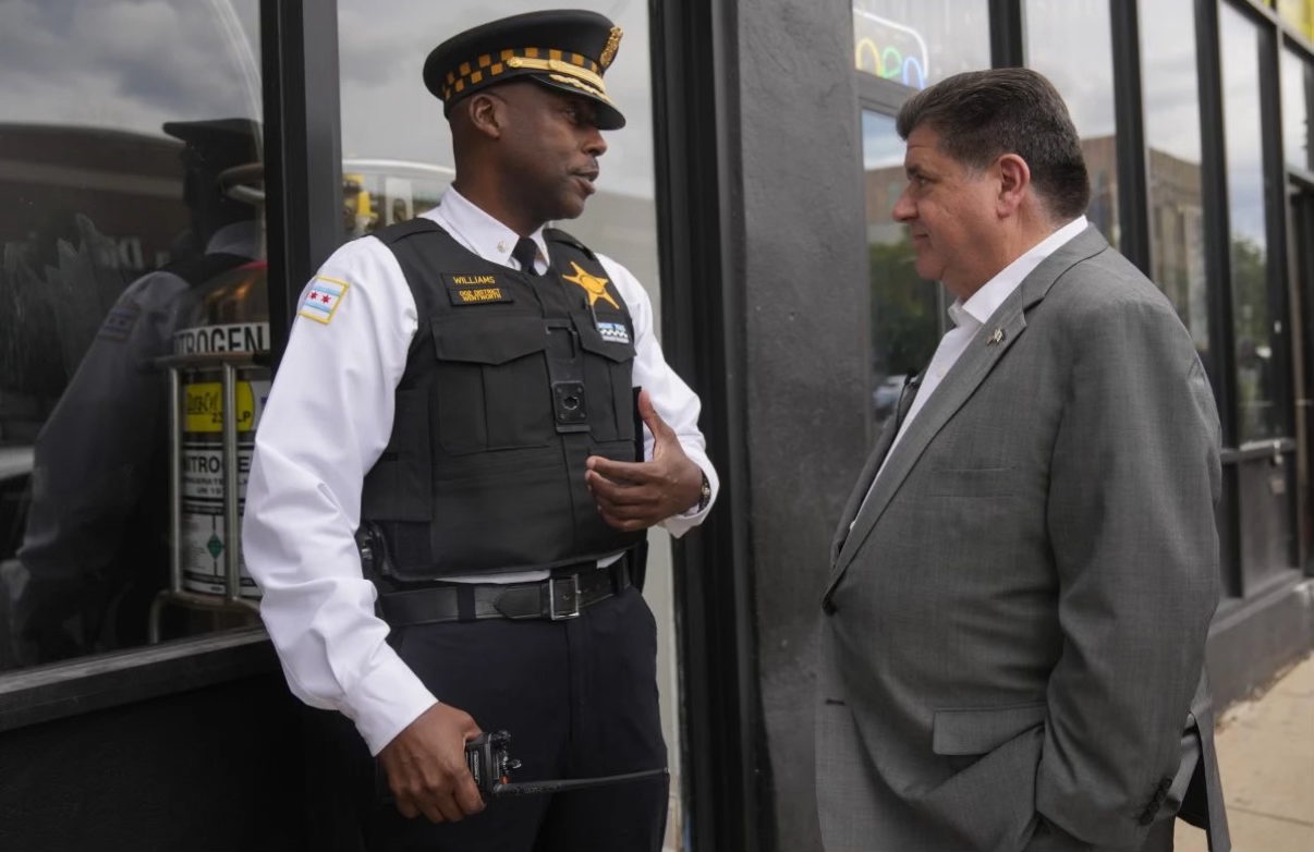 Gov. Pritzker speaks with a Chicago police officer in the Bronzeville neighborhood of Chicago. (Erin Hooley/AP)