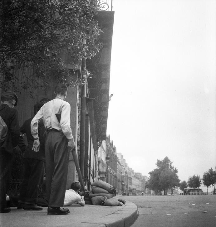 Armed Parisians take cover behind a small barricade and a corner of the building at the intersection of Rue de Seine, Square Honoré Champion and 3, Quai Malaquais, looking out over the Quai Malaquais towards the Pont du Carrousel. AKG10620263 © René Zuber / akg-images