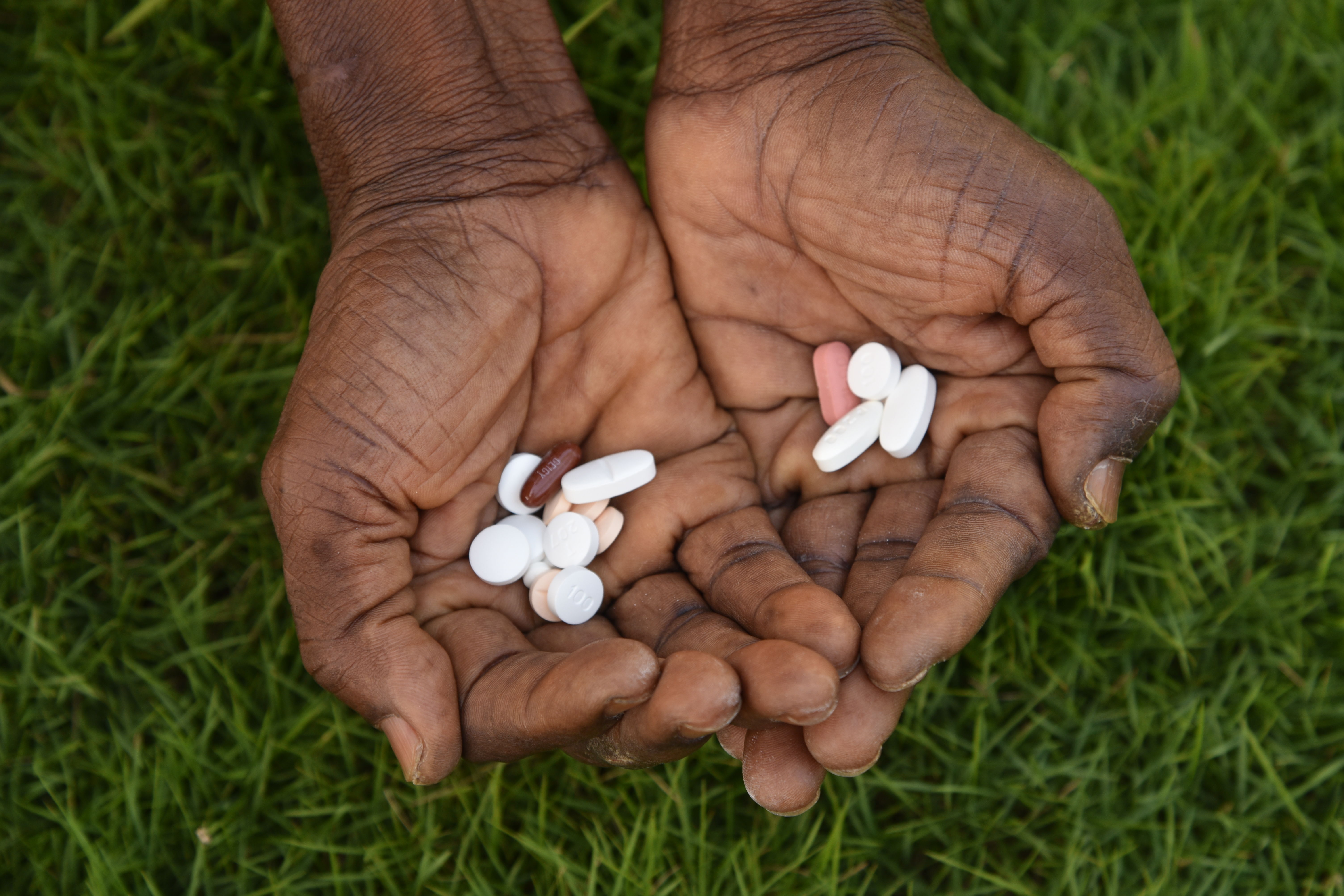 Image of medicine for the treatment of drug resistant tuberculosis (DR-TB). The left hand contains pills from the recently approved BPaLM 6-month shorter regimen treatment and the right hand contains pills from the longer 18 months regimen treatment. Following the validation of shorter regimen by WHO, MSF started supporting the Ministry of Health in implementing shorter regimen for patients affected by DR-TB since 2022 in Sierra Leone. Depending on individual patients’ diagnostic and clinical situation treatment regimens are initiated. Shorter regimens are often preferred by patients and medical professionals as longer treatment can be physically and mentally harder to adhere to. | Date taken: 14/12/2023 | Photographer: Ammar Obeidat