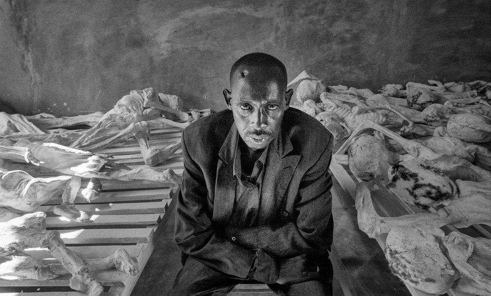 Emanuel Murangira, a surviving Tutsi, with exhumed bodies in a school (now a genocide museum) in Murambi near Gikongoro, Rwanda. A bullet hole is visible on his head.