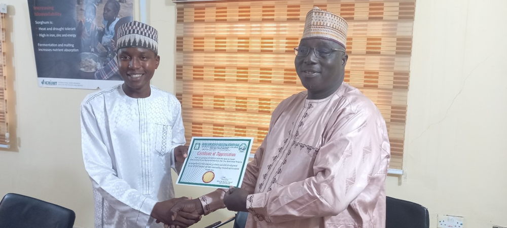 Dr Angarawai Ignatius ICRISAT Country Rep Nigeria Receiving certificate of appreciation from Mr Musba’ab Bashir, President of NAAS, Aloko Dangote University of Science and Technology Wudil.