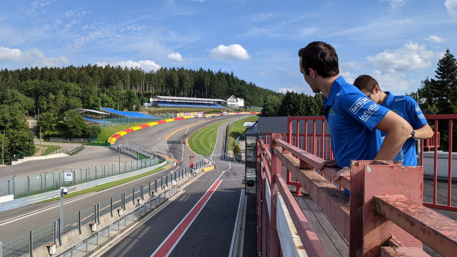 Teamleden kijken toe hoe de zonnewagen door het circuit rijdt.